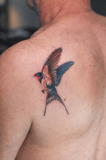 Tatuaje minimalista de una golondrina en el cuello